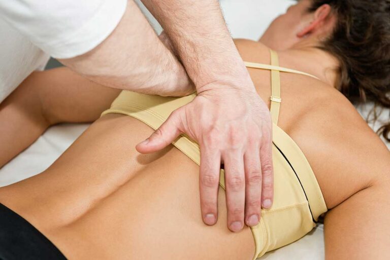 A chiropractor demonstrating spinal alignment on a model of the human spine.