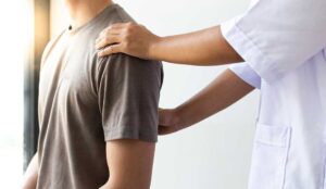 Adult receiving gentle spinal care while discussing neck tension with a practitioner in a quiet treatment room.